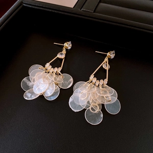 Detailed close-up of bamboo-style gold hoop earrings with layered seashell pendants