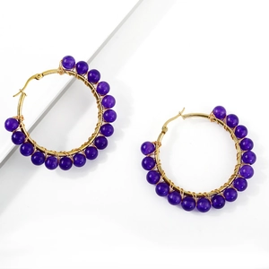 Detail of bohemian gold hoop earrings with purple beads and wire-wrapped craftsmanship