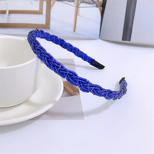 Detail of blue beaded braided headband resting on a white ceramic teacup and saucer