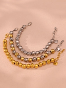 Detailed close-up of 10mm hollow bead bracelets in gold and silver with heart charms
