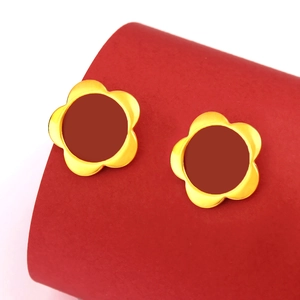 Elegant gold flower stud earrings with ruby red centers on a luxury display stand