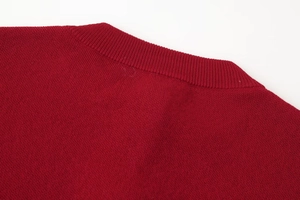 Close-up of red knitted cardigan featuring ribbed crew neck and fine stitch texture