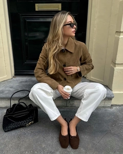 Gros plan d'une veste en daim marron avec pantalon blanc et sac à main tressé