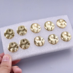 Detail view of nine gold vintage stainless steel stud earrings set on a white foam block