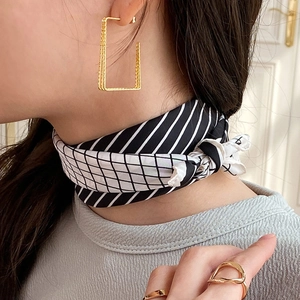 Close-up of a black and white striped silk scarf knotted around the neck of a model