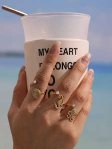 Detail of gold ocean rings with zircon starfish and seahorse on a beach setting