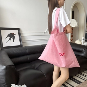 Detail of pink canvas tote bag with red Day Light print shown in modern home interior