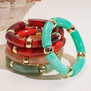 Close-up of stacked acrylic resin bracelets with marble texture and gold spacer rings