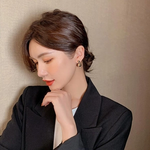 Detail view of a model wearing minimalist golden double ball earrings with a black blazer