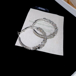 Detailed close-up of silver hoop earrings with sparkling pave-set zircons on black backdrop