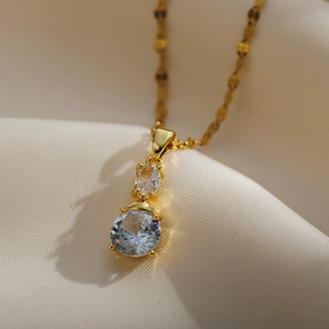 Detailed close-up of a gold dual-zircon pendant necklace on elegant satin fabric