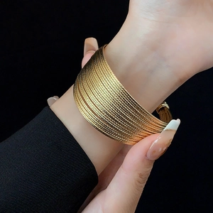 Detailed view of layered gold-plated metal cuff bracelet with fine woven mesh texture