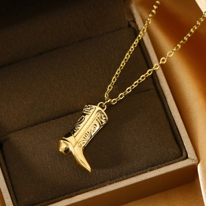 Golden western cowboy boot pendant necklace with vintage engravings on a satin background