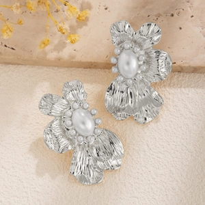 Detail van vintage zilveren bloemoorbellen met witte parels op een stenen achtergrond