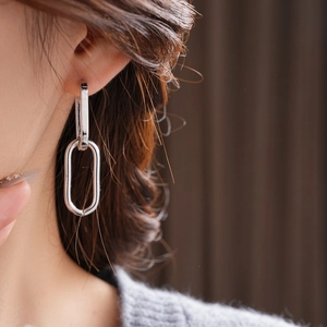 Close-up of elegant silver oval link chain earrings worn by a model in soft lighting