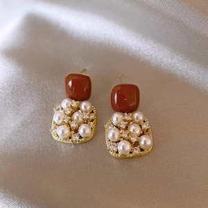 Macro detail of vintage gold square earrings with brown resin and micro-pave pearls