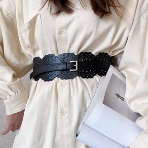 Ceinture large noire ajourée avec boucle dorée sur une robe beige élégante