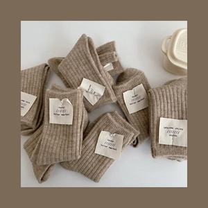 Detailed view of folded thick wool socks in beige and light brown with small brand labels