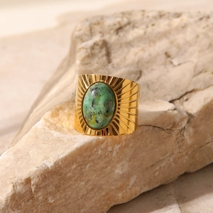 Macro detail of vintage gold textured wide band ring featuring an oval green turquoise stone