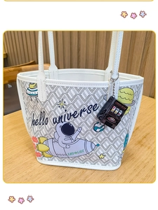 Close-up of white tote bag with astronaut pattern and mini slot machine keychain charm
