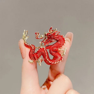 Close-up of red beaded dragon brooch with gold-tone plating details and metal base