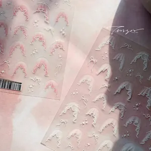Detail of pink dreamy nail stickers with white lace patterns and bow designs