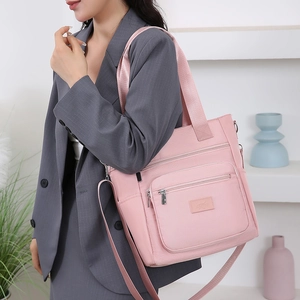 Pink oxford cloth shoulder bag with multiple zippers and wide strap on model