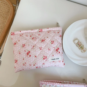 Pink floral quilted cotton makeup bag with simple wish label on beige tabletop