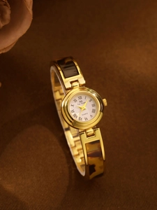 Detail of gold watch with amber tortoiseshell chain links and Roman numeral dial