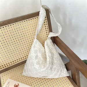 Détail de la texture jacquard à fleurs blanches sur un sac à bandoulière hobo pour femme