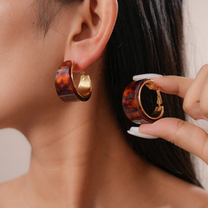 Close-up of tortoise shell resin C-shaped hoop earrings with gold accents on model