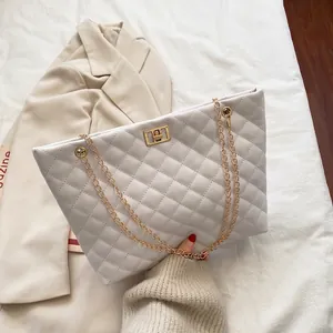 White quilted tote bag with gold chain strap and turn-lock closure in elegant urban style