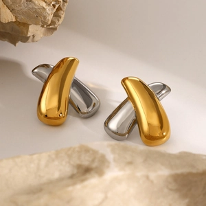 Macro detail of chunky X-shaped earrings in polished gold and silver stainless steel