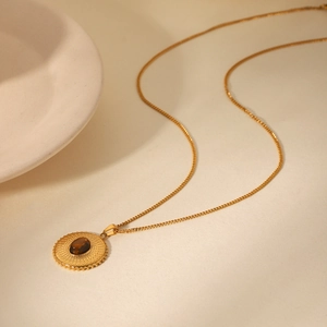 Detail of round tiger eye stone pendant on vintage gold textured stainless steel chain