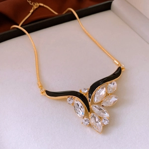 Detailed shot of vintage gold necklace with black enamel and crystals in a luxury gift box