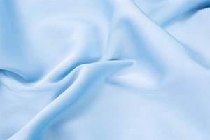 Macro di tessuto satinato azzurro che mostra l'elegante trama a pieghe e il riflesso seta