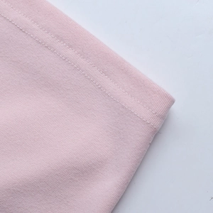 Vista macro della doppia cucitura rinforzata sul tessuto dell'abito in maglia rosa