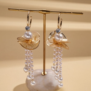 Detail of gold fan-shaped earrings with cascading pearl tassels on a jewelry display