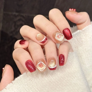 Uñas postizas rojas y doradas festivas con el carácter 'Xi' para el Año Nuevo Chino