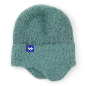 Detailed view of turquoise plush knit winter hat with snowflake patch and ear flaps