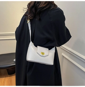 Close-up of light gray glossy leather underarm bag featuring a golden rectangular clasp