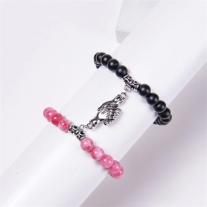 Close-up of magnetic hand charms connecting black and pink natural stone couple bracelets