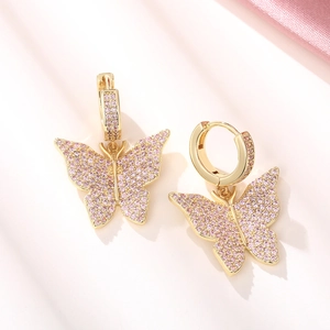 Detail of gold butterfly earrings with pink cubic zirconia on elegant silk fabric