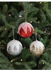 Gros plan de boules de Noël scintillantes rouges et dorées avec mousse effet neige sur l'arbre