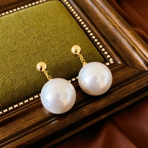 Close-up of vintage gold sphere earrings with large pearls on green velvet background