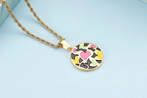 Macro view of golden twist chain and colorful enamel round pendant with pink heart pattern