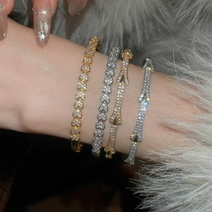 Détail de joncs plaqués or 18 carats avec cœurs et flèches en strass sur le poignet