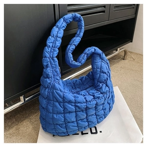 Detail of electric blue quilted bubble handbag with soft nylon texture and grid pattern