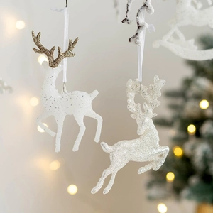 Sparkling white and gold glitter reindeer ornaments hanging on a Christmas tree branch