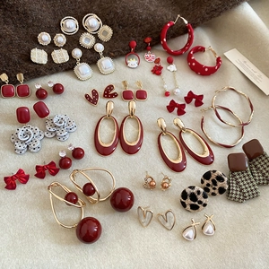 Detail of luxury pearl and red enamel earring set with gold accents on knit background